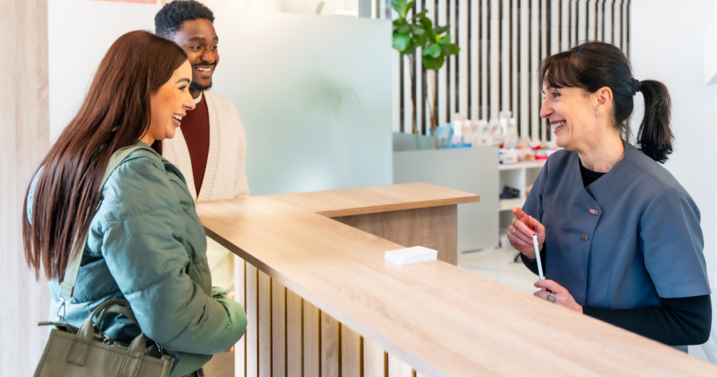 dental receptionist checking in patient with welcoming front desk